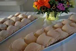 Trays of date mango empanadas beside a bouquet of fresh flowers