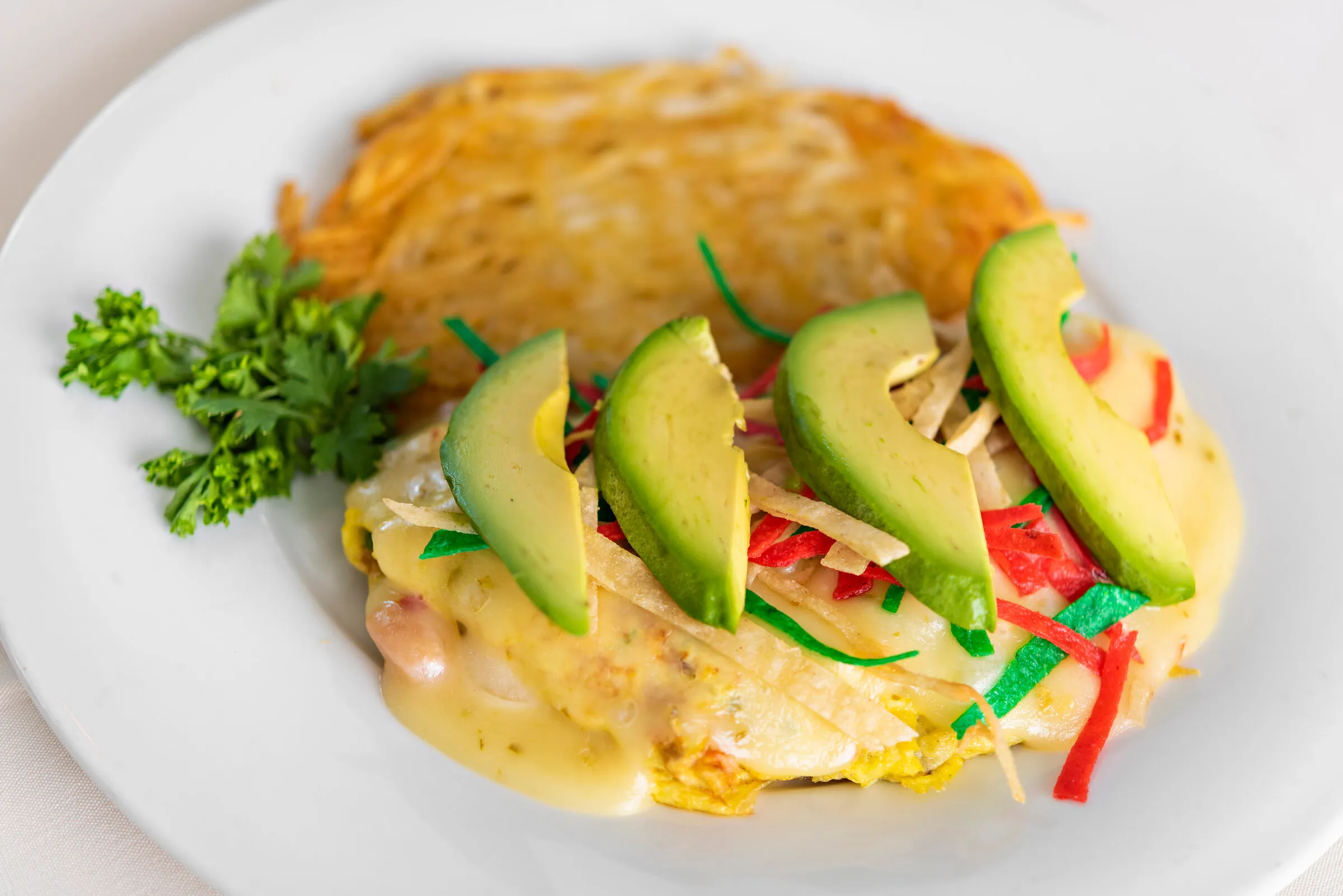 Breakfast plate with hollandaise, sliced avocado, and a crispy hash brown