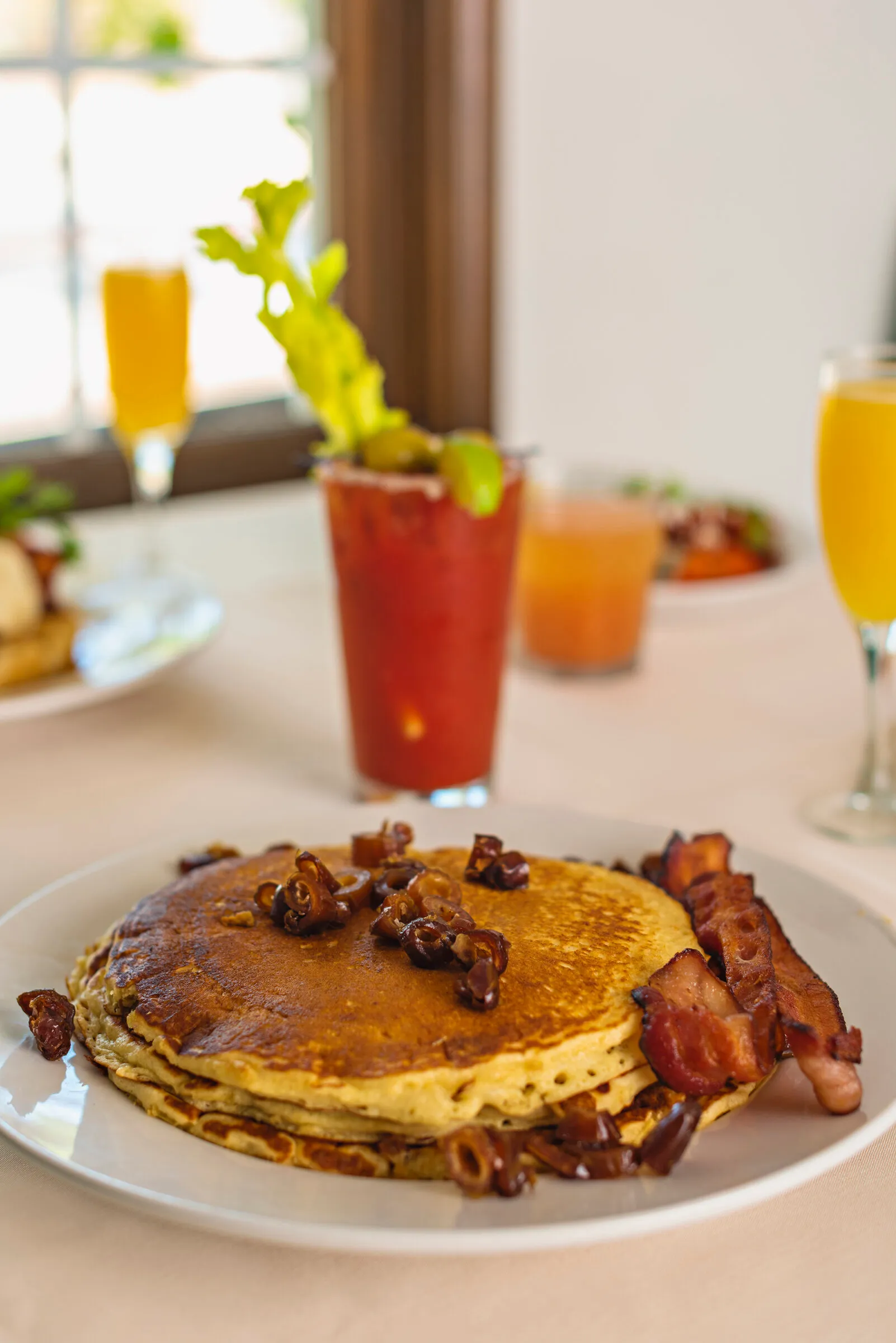 Pancakes topped with candied nuts, served with bacon and a Bloody Mary