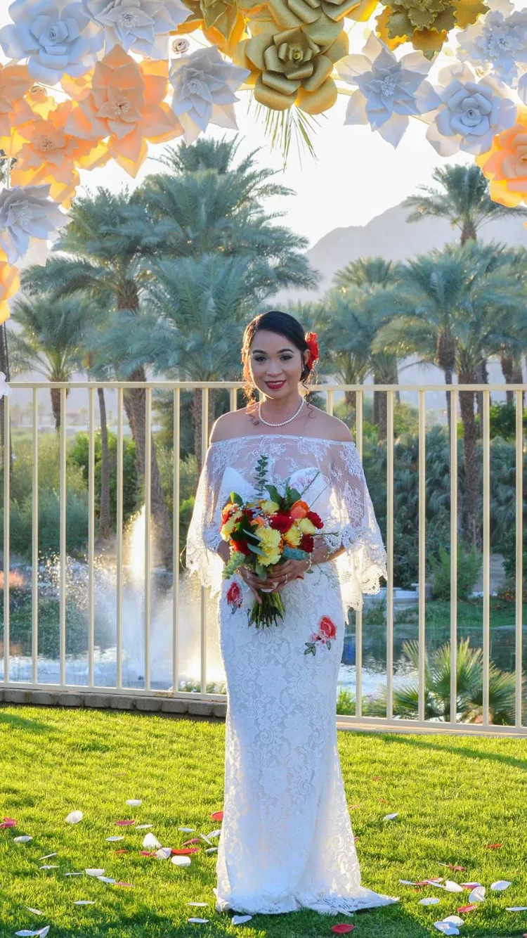 Bride with a colorful bouquet on the lawn overlooking the lake and palm trees