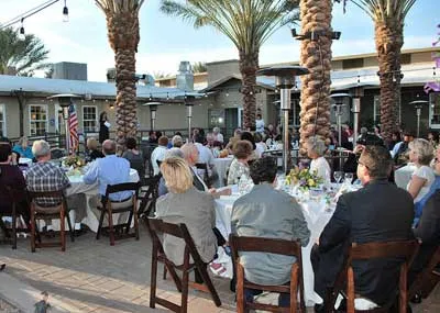 Large catered event with guests seated on the palm-lined patio