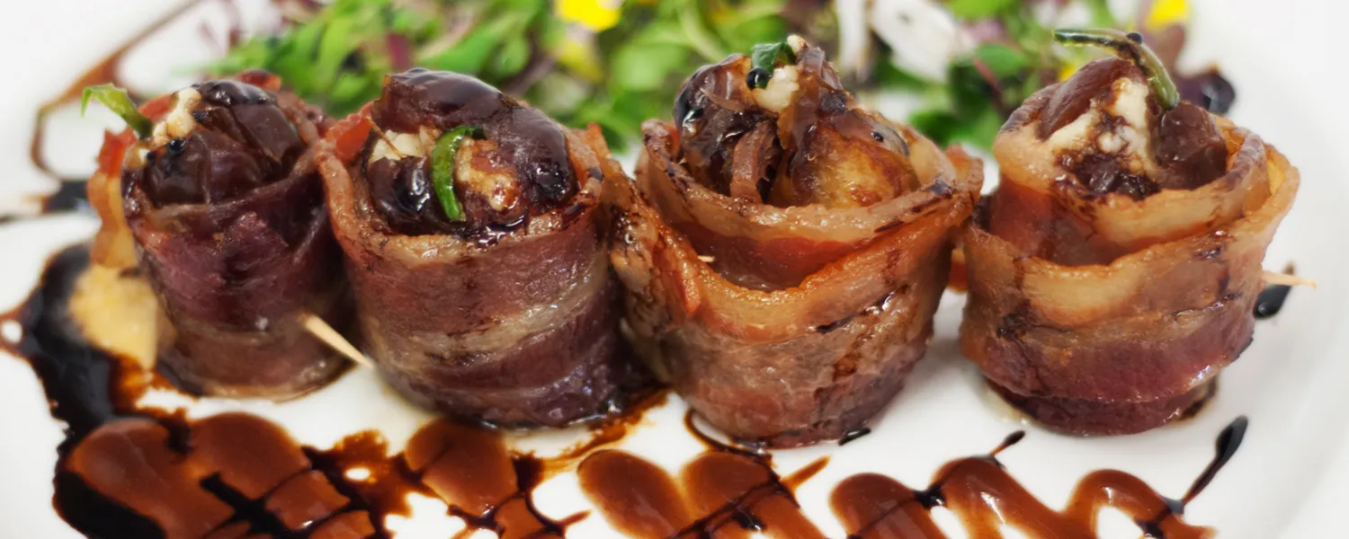 Bacon-wrapped stuffed Medjool dates drizzled with balsamic glaze